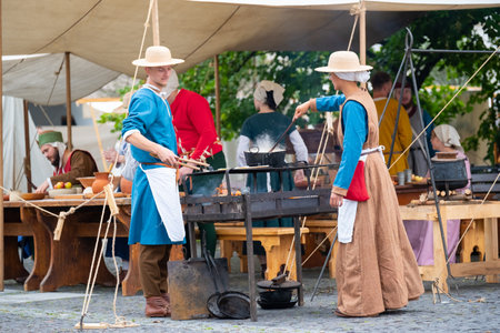 Zilina, Slovak RepubliÑ, Slovakia - July 28, 2023: Man woman preparing natural flatbread on fire during traditional annual medieval ages restoration day known as "Stredoveky den" in Zilina, Slovakia.のeditorial素材