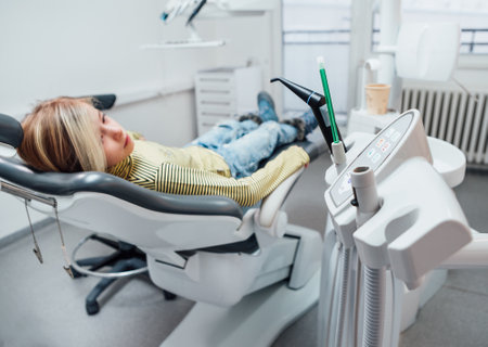 Medical dental chair vacuum instruments photo. Little girl sitting in stomatology clinic chair after teeth dental procedures. Healthcare, kid's health and medicare industry concept image.の写真素材
