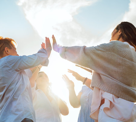 Portrait of four cheerful laughing women holding hands Up making High Five during outdoor walking. They looking at the camera. Woman's friendship, natural diversre beauty, relations, happiness imageの写真素材