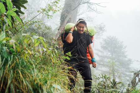 Portrait of strong Sherpa man working as porter carrying huge cargo with traditional method on forehead. High Himalayas expedition during Mera peak climbing. Transportation or goods delivery conceptの写真素材
