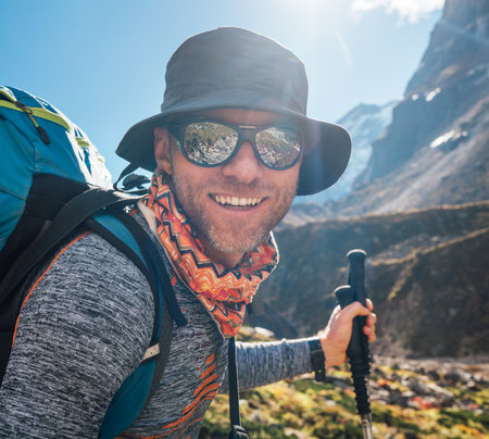Portrait Young hiker backpacker man in sunglasses smiling at camera in Makalu Barun Park route during high altitude acclimatization walk. Mera peak trekking route, Nepal. Active vacation concept imageの写真素材