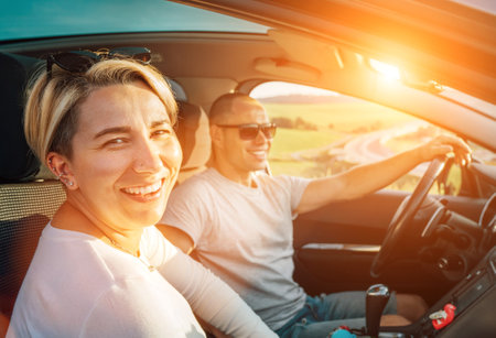 Portrait of cheerful smiling young woman with husband have auto journey inside modern car. Safety riding car, car sharing and traveling concept image.の写真素材