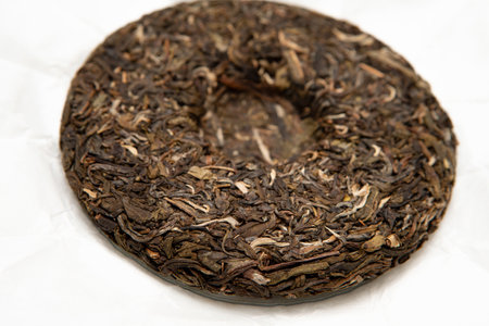 Pressed raw pu-erh tea cake showcasing natural loose-leaf texture and details of aged tea leaves symbolizing craftsmanship tradition in tea preparation, perfect for authentic tea lovers and collectorsの写真素材