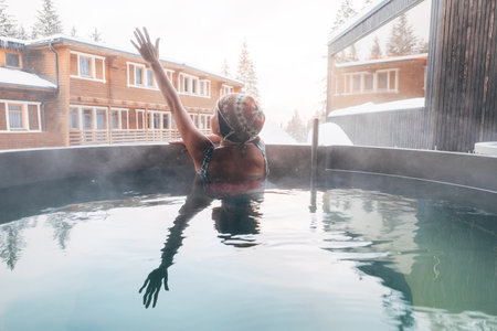 Young woman relaxing in Hot water bathtub outdoor bathtub in winter forest wellness hotel and enjoying pleasant healthy body care temperature treatment. Healthy body care and vacation concept.の写真素材