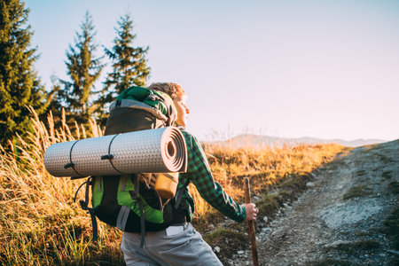 Little boy backpacker walking up mountain top in Mala Fatra, Slovakia, enjoying sunny rays. Active teenager embracing adventure and outdoor exploration, perfect for family activities and nature loversの写真素材
