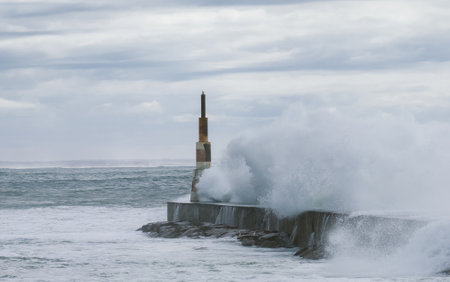 Huge waves crashing over Breakwater during winter storm Atlantic waves washing the lighthouse on Praia da Aguda sandy beach at Aguda settlement near Porto, Portugal.の写真素材