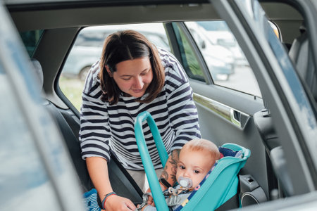 Mother is securing her baby in car seat, ensuring child's safety before driving. Scene captures moment of care and responsibility, highlighting importance of child safety during car travelの写真素材