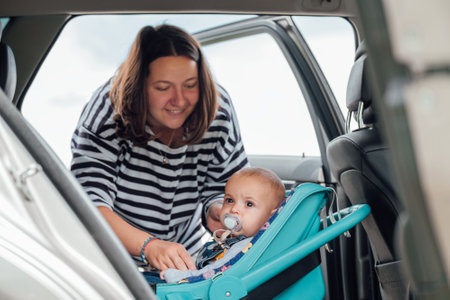 Mother is securing her baby in car seat, ensuring child's safety before driving. Scene captures moment of care and responsibility, highlighting importance of child safety during car travelの写真素材