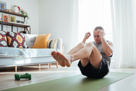 Muscular man doing an abdominal exercise on the living room floor. Healthy lifestyle or active people concept image.の写真素材