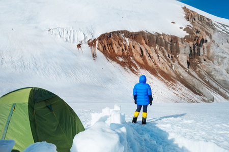Lonely mountaineer woman in high mountaineering clothes enjoying Kazbek 5054m mountain standing at advanced base camp site, Caucasus, Georgiaの写真素材