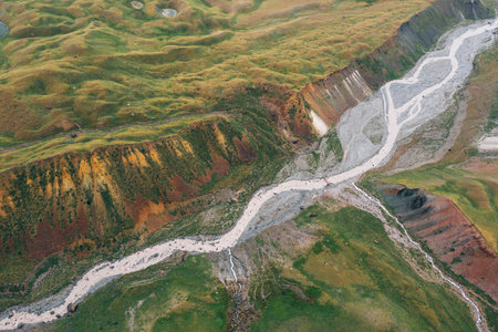 Incredible aerial shot of mountain river with tributaries surraunded green hills deep in Pamir...