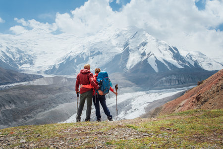 Backpackers couple with backpacks hugging enjoying Pamir mountains during Lenin peak ascent with...