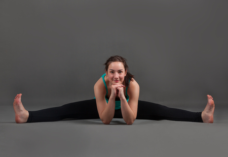 beautiful woman doing yoga   upavishta konasana on a gray backgroundの写真素材