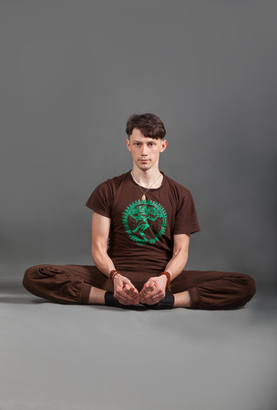 beautiful man doing yoga  baddha konasana on a gray backgroundの写真素材