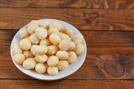 delicious macadamia nuts on a plate on a wooden backgroundの写真素材