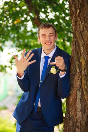 Happy beautiful bridegroom standing on the street and smilingの写真素材