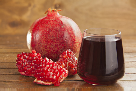 delicious juice from ripe pomegranate in beautiful glass on a wooden tableの写真素材