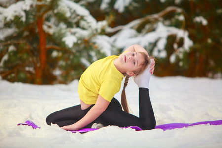 beautiful woman doing yoga outdoors in the snow in yellow T-shirt