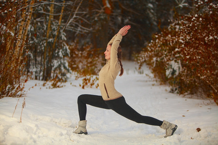 beautiful woman doing yoga outdoors in the snowの写真素材