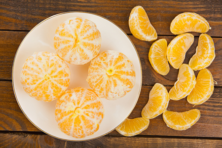 ripe juicy Spanish mandarins on plate on a wooden backgroundの写真素材