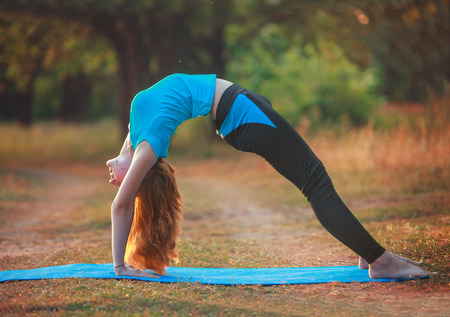 beautiful woman doing yoga outdoors On the green grass