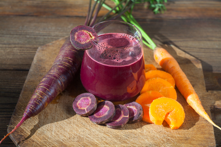 Carrot juice in glass on a wooden tableの写真素材