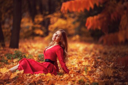 beautiful woman in the autumn in the red forest walksの写真素材
