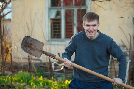 Agronomist handsome strong man with shovel on the background of flower bedsの写真素材