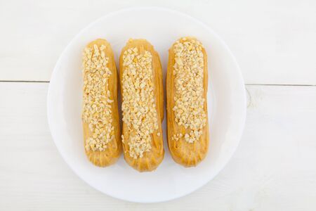 Tasty appetizing french eclairs on a white plate on a white backgroundの写真素材