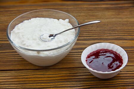 Tasty fresh grained cottage cheese on a plate on a wooden tableの写真素材