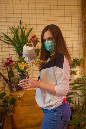 beautiful girl gardener caring for flowers in a greenhouseの写真素材