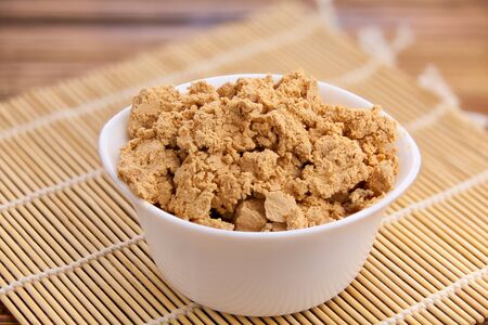 Tasty fresh grained cottage cheese on a plate on a wooden table
