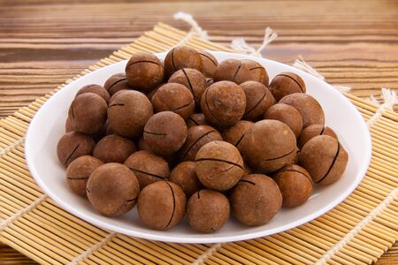 delicious macadamia nuts on a plate on a wooden backgroundの写真素材