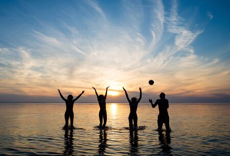 people in the sea at sunset play ballの写真素材