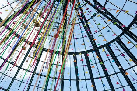Multicolored easter eggs, ribbons, flags and wreaths  under a glass roofの写真素材