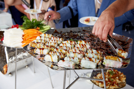 men in blue suits choosing food at a banquetの写真素材