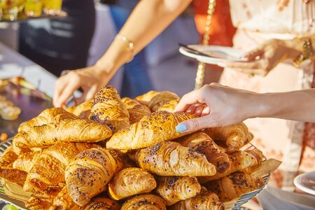 Female hands taking croissants at a banquet at a conferenceの写真素材