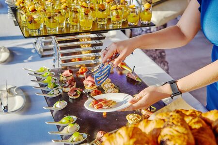 Female hands taking food at a banquet at a conferenceの写真素材