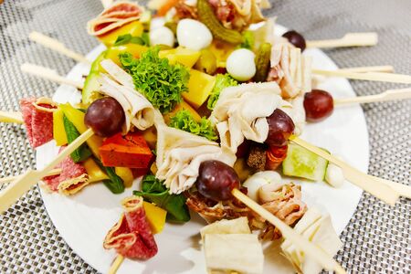 Vegetable kebabs lying on a white plate photographed close upの写真素材