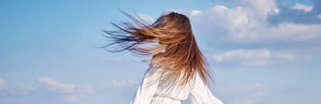 woman in white dress happy on a background of sky with cloudsの写真素材