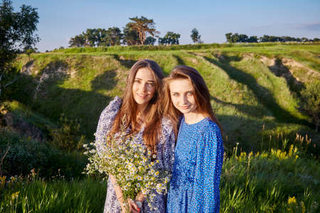 two young beautiful girls with a bouquet of flowers in natureの写真素材