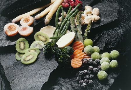 frozen fruits and vegetables on black stonesの写真素材