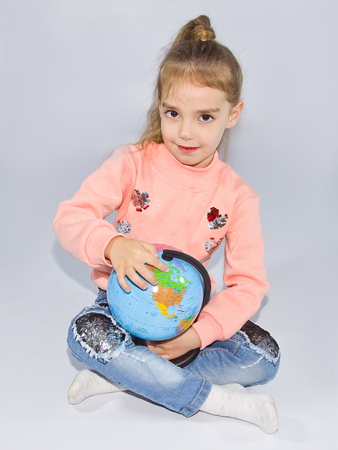 little girl sits and holds a small globeの写真素材