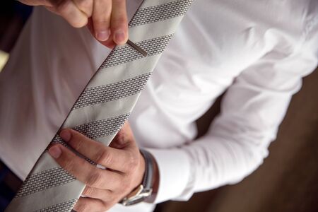 Man clipping a necktie with a tie bar close up lifestyle detail shot.の写真素材