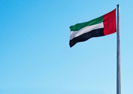 UAE National Flag of United Arab Emirates Waving on Sunny Blue Sky Clean Backgroundの写真素材