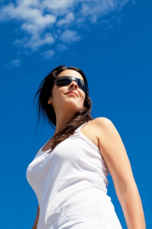 Young Woman Smiling with a Bright Blue Sky Backgroundの写真素材