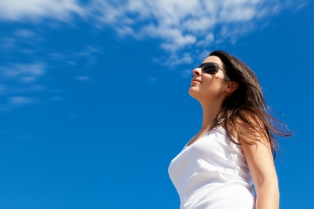Young Woman Smiling with a Bright Blue Sky Backgroundの写真素材