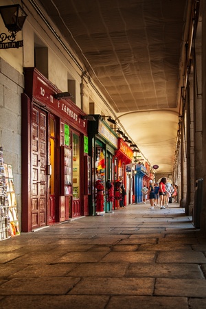 MADRID, SPAIN - AUGUST 12  People walking through a corridor of the Plaza Mayor, one of the popular landmarks of the city where many tourist shops are located, on August 12, 2013 in Madrid, Spainのeditorial素材