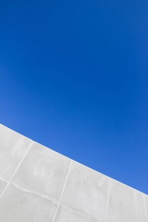 Inclined raw concrete rendered wall with blue sky backgroundの写真素材