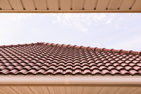 Roof tiles and rain gutter horizontal view against blue sky background